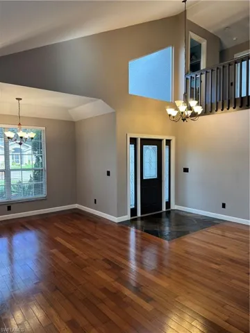 Entryway with a chandelier, hardwood / wood-style flooring, plenty of natural light, and high vaulted ceiling