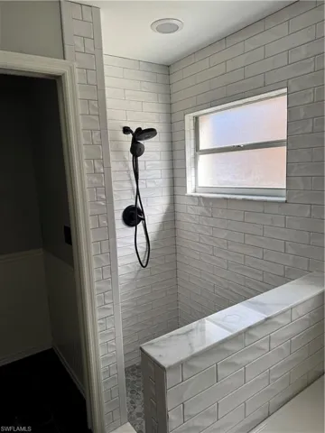 Bathroom featuring a tile shower and a wainscoted wall