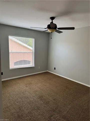 Spare room featuring dark carpet and a ceiling fan
