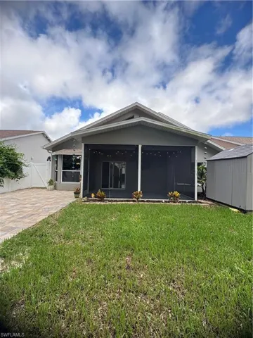 View of front facade with a front yard, a sunroom, and a shed