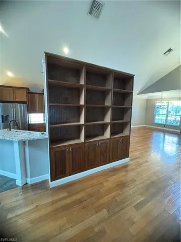 Detailed view of fridge, light wood finished floors, light stone counters, and a chandelier