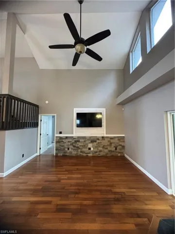 Unfurnished living room featuring high vaulted ceiling, wood finished floors, and ceiling fan