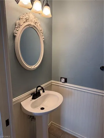 Bathroom featuring a textured wall, a wainscoted wall, and tile patterned floors