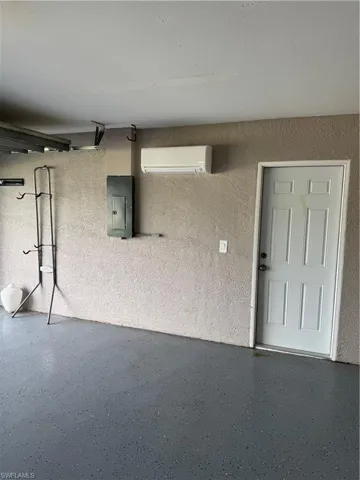 View of exterior entry featuring electric panel and a wall unit AC