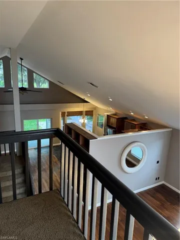 Stairs featuring vaulted ceiling, a chandelier, wood finished floors, and ceiling fan