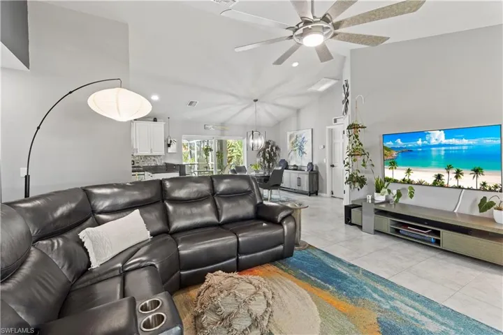 Living room featuring lofted ceiling, light tile patterned floors, and ceiling fan