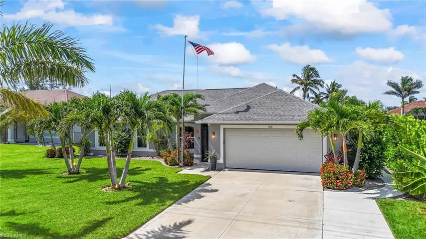 View of front facade with a shingled roof, an attached garage, concrete driveway, a front yard, and stucco siding