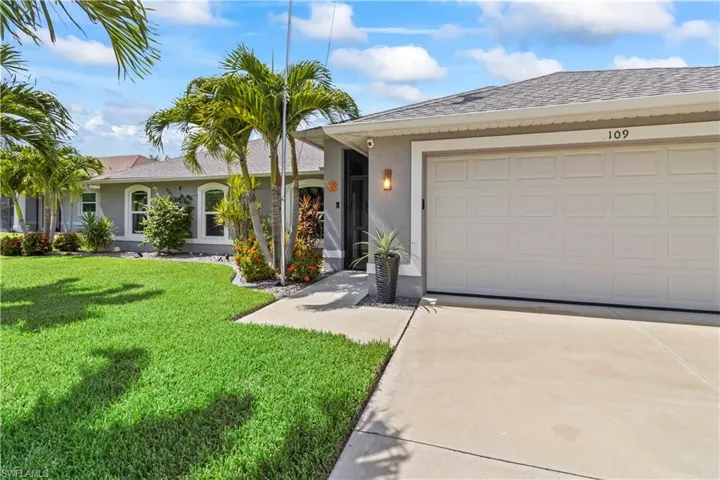 View of front of home featuring roof with shingles, a garage, driveway, a front lawn, and stucco siding