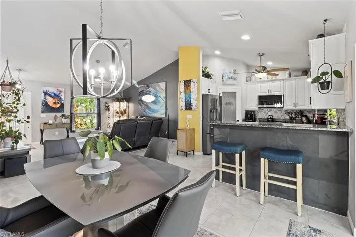 Kitchen featuring lofted ceiling, appliances with stainless steel finishes, tasteful backsplash, white cabinetry, and ceiling fan