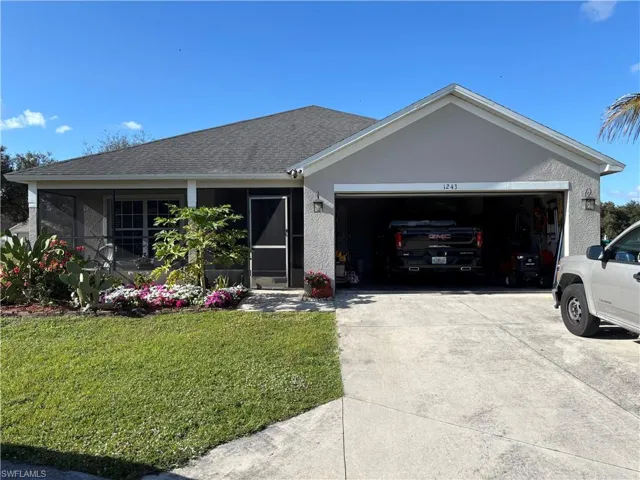 Ranch-style home with a front lawn, a garage, driveway, roof with shingles, and stucco siding