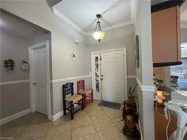 Foyer featuring light tile patterned floors and crown molding