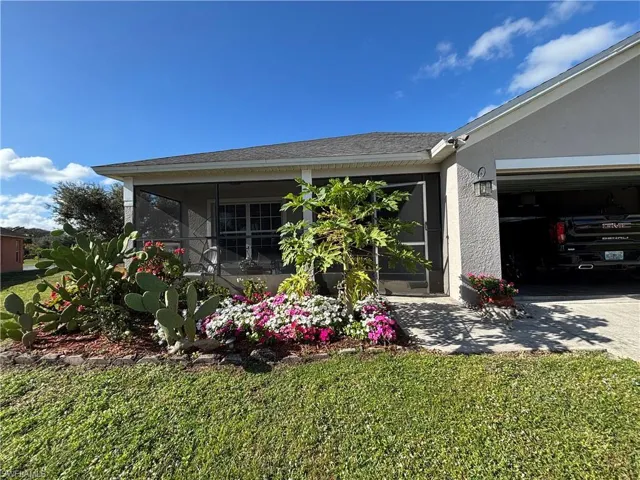 View of home's exterior featuring a sunroom, a yard, stucco siding, a garage, and driveway