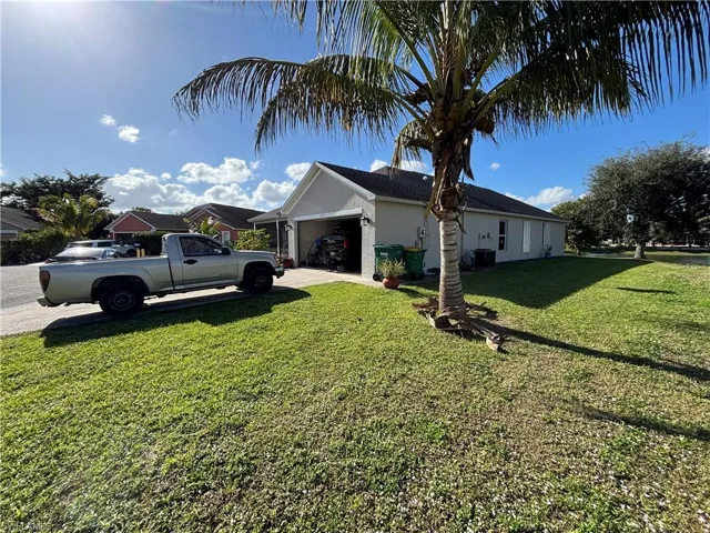 View of side of home with a yard, a garage, concrete driveway, and stucco siding