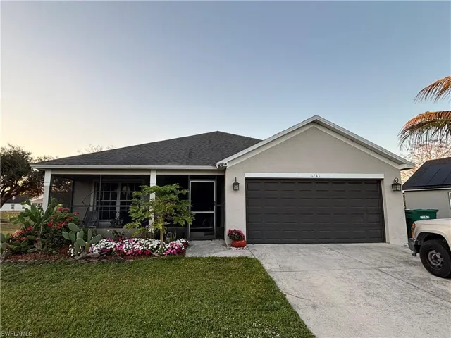 Ranch-style house with a front yard, a sunroom, a garage, stucco siding, and concrete driveway