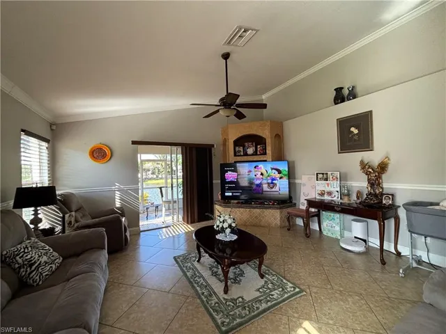 Living room with ornamental molding, ceiling fan, lofted ceiling, and healthy amount of natural light