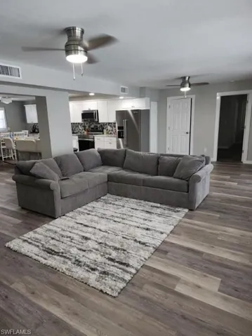 Living room with dark hardwood / wood-style floors and ceiling fan
