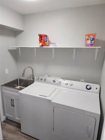 Washroom featuring sink, cabinets, washing machine and dryer, and dark wood-type flooring