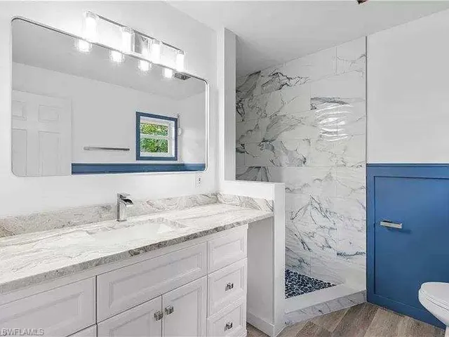Bathroom featuring hardwood / wood-style floors, toilet, vanity, and a tile shower