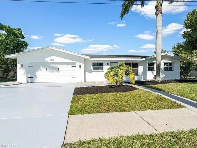 Ranch-style home featuring a garage and a front lawn