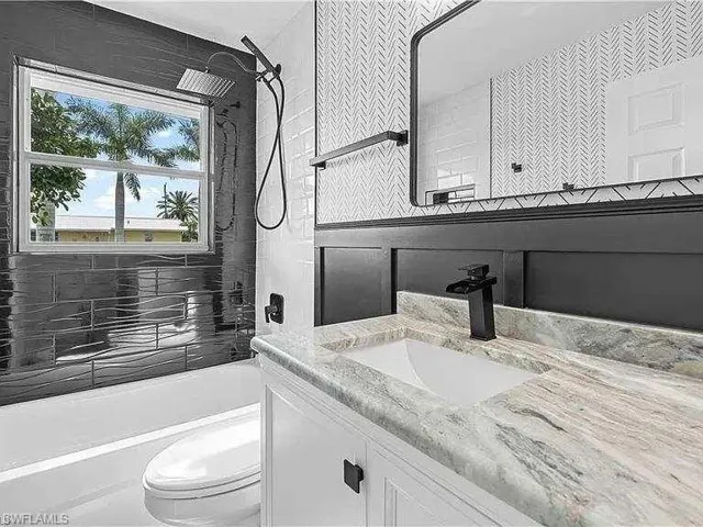 Full bathroom with vanity, tiled shower / bath, decorative backsplash, and toilet