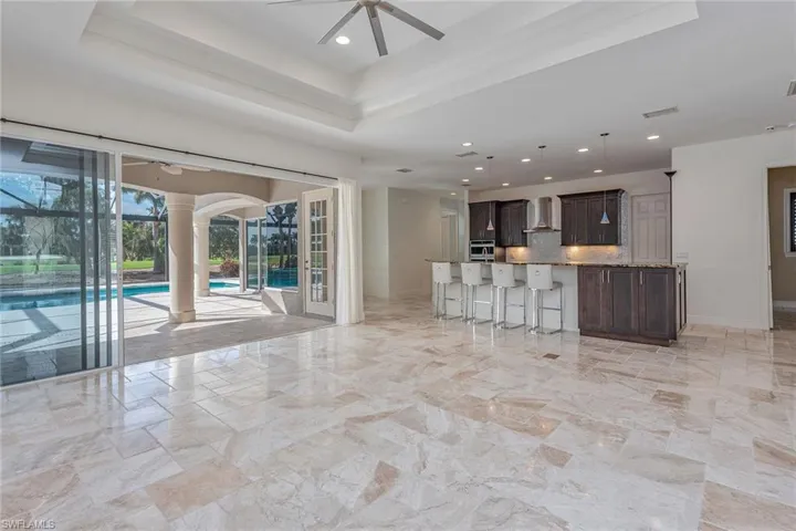 Kitchen featuring dark brown cabinets, open floor plan, backsplash, a raised ceiling, and recessed lighting