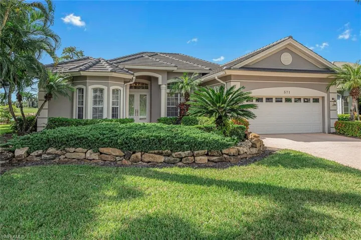 View of front facade featuring stucco siding, driveway, a front lawn, an attached garage, and french doors