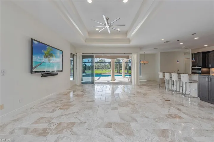 Unfurnished living room with a chandelier, a raised ceiling, recessed lighting, and a sunroom