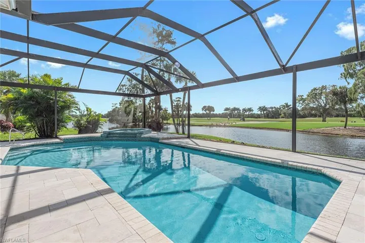 View of pool featuring a water view, a lanai, a pool with connected hot tub, a sunroom, and a patio