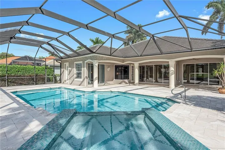 View of swimming pool featuring a sunroom, a pool with connected hot tub, glass enclosure, and a patio