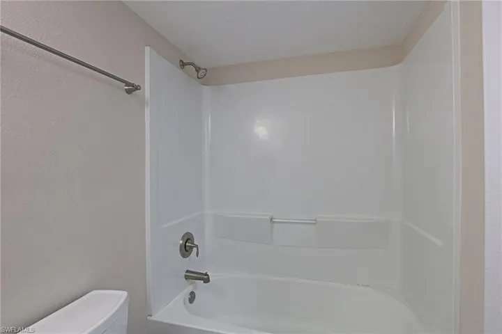 Bathroom featuring a textured wall and shower / washtub combination