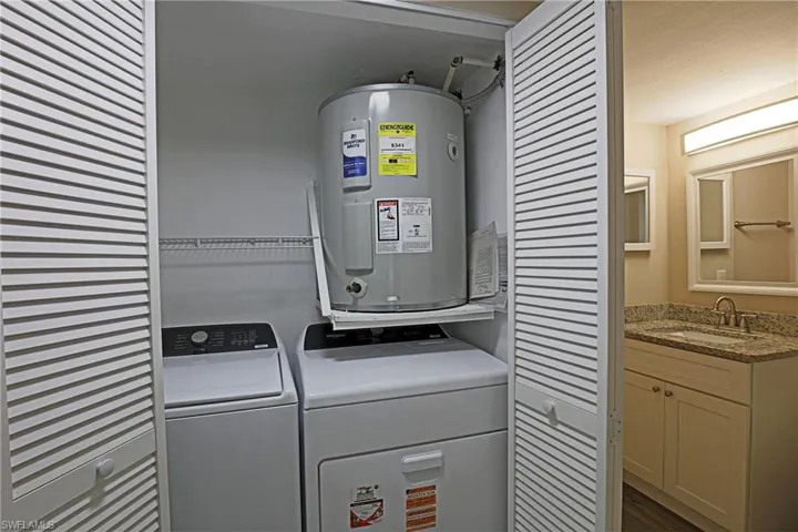 Laundry area with water heater and washing machine and clothes dryer