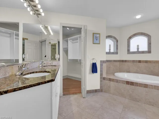 Bathroom featuring tile patterned flooring, double vanity, a garden tub, and a spacious closet