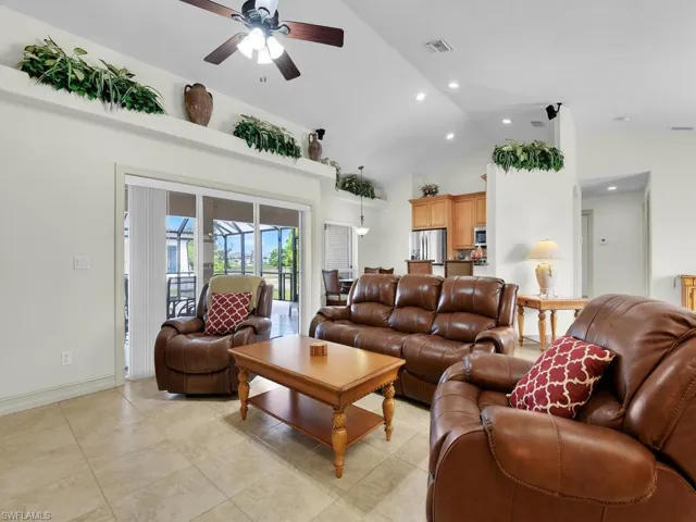 Living room featuring ceiling fan, high vaulted ceiling, light tile patterned floors, recessed lighting, and baseboards