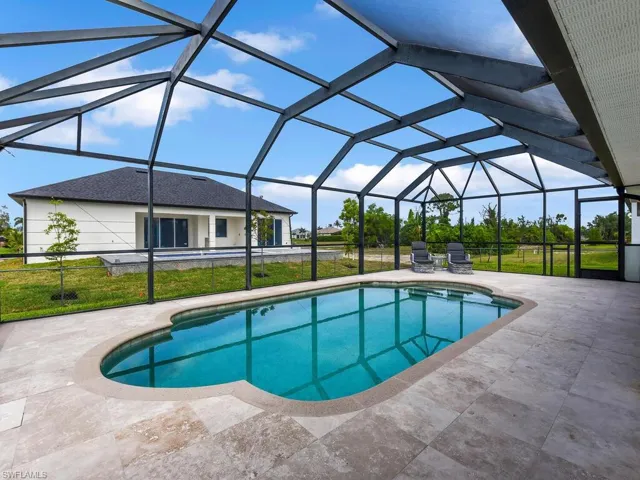 Outdoor pool featuring a patio, glass enclosure, and a lawn
