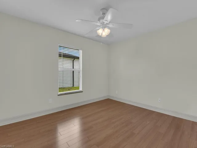 Empty room featuring wood finished floors, baseboards, and ceiling fan