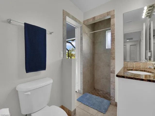 Full bathroom with toilet, vanity, tiled shower, and tile patterned floors
