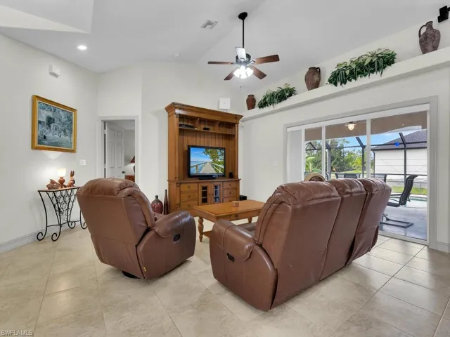 Living room with a ceiling fan, light tile patterned flooring, vaulted ceiling, baseboards, and recessed lighting