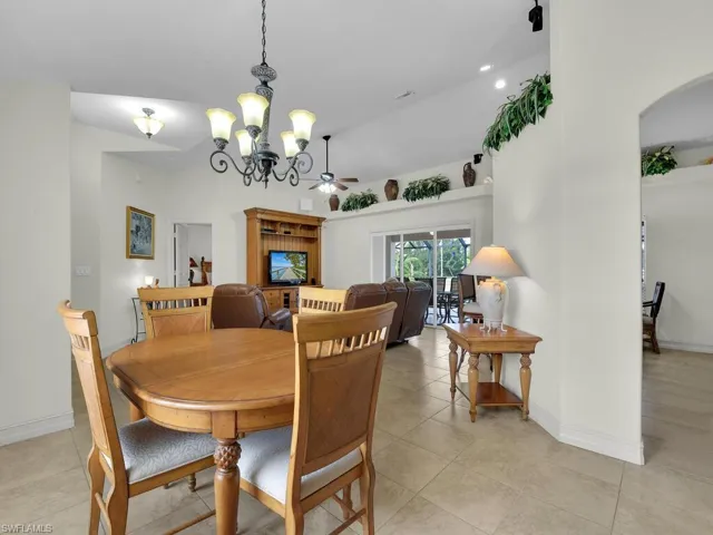 Dining area featuring a chandelier, arched walkways, baseboards, and light tile patterned floors