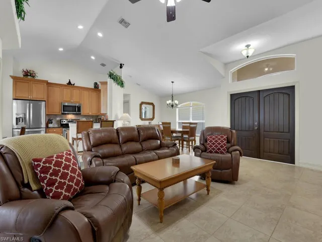 Living area with a chandelier, ceiling fan, recessed lighting, high vaulted ceiling, and light tile patterned floors