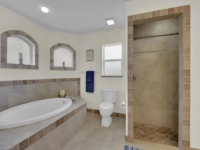 Full bathroom with toilet, a bath, a stall shower, and tile patterned flooring