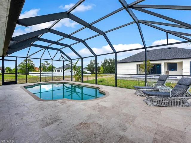 Outdoor pool featuring a patio area, a lawn, and glass enclosure