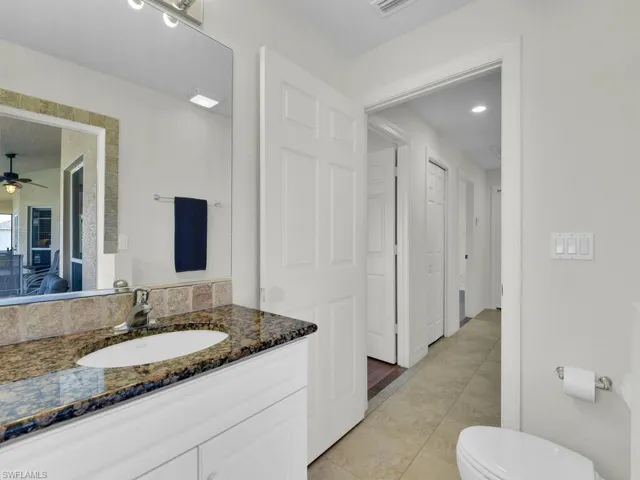 Ensuite bathroom featuring vanity, tile patterned flooring, toilet, and ceiling fan