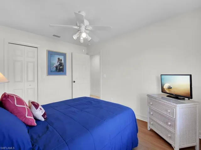 Bedroom with wood finished floors, a ceiling fan, a closet, and baseboards