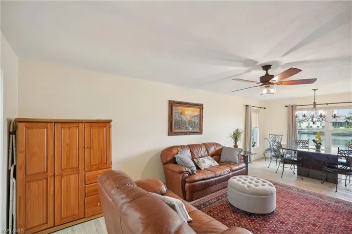 Living room with ceiling fan with notable chandelier and light wood-type flooring
