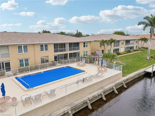 View of swimming pool featuring a lawn, a water view, and a patio
