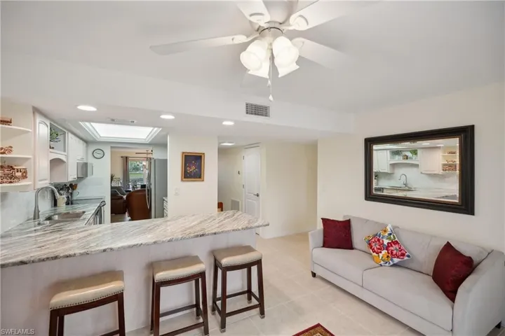 Kitchen with kitchen peninsula, white cabinets, a breakfast bar area, and sink