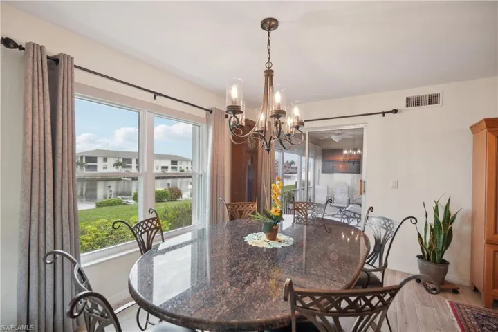 Dining space with light wood-type flooring, a healthy amount of sunlight, and a notable chandelier