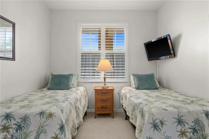 Twin beds flanking a central window with white plantation shutters