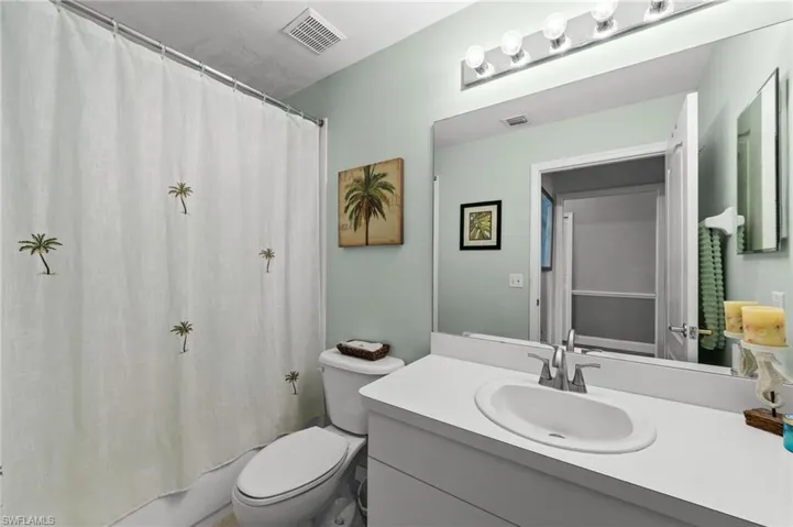 Bathroom featuring a vanity with an integrated sink, a large wall-mounted mirror, and a wall-mounted light fixture