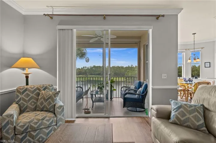 Sliding glass doors open to a screened balcony overlooking a tranquil water feature and mature foliage